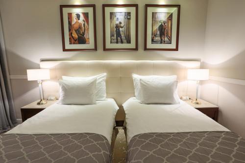 two beds in a hotel room with pictures on the wall at Hotel International Iasi in Iaşi