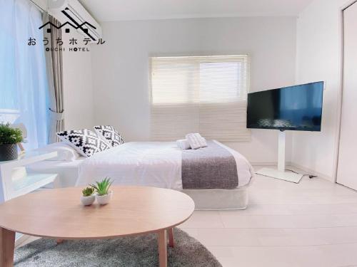 a bedroom with a bed and a table and a tv at OUCHI HOTEL Hatsukaichi-Ekimae in Hatsukaichi