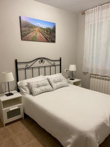 a bedroom with a white bed with two nightstands and two lamps at Casa MARIA VILLARROYA in Villarroya