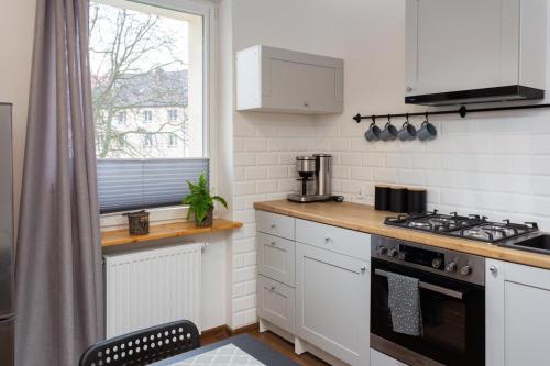 d'une cuisine avec des placards blancs, une cuisinière et une fenêtre. dans l'établissement Apartament Studzienna 18, à Szczecin