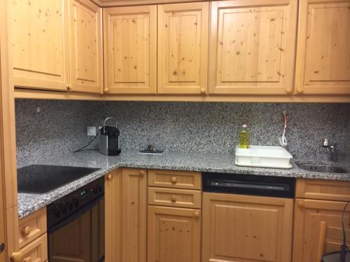 a kitchen with wooden cabinets and granite counter tops at 2-Zimmer Ferienwohnung Bünda in Davos