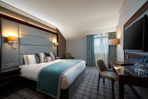 ein Hotelzimmer mit einem Bett, einem Schreibtisch und einem TV in der Unterkunft Kilmurry Lodge Hotel in Limerick