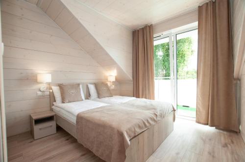 een slaapkamer met een groot bed en een groot raam bij Domki Amber House in Dźwirzyno