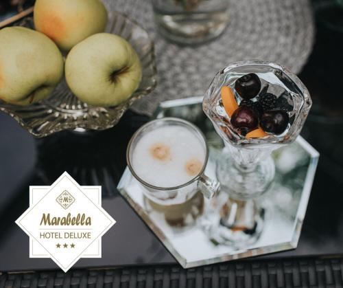 a table with a glass bowl of fruit and a drink at Hotel Marabella in Sibiu