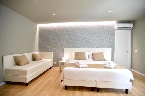 1 dormitorio con 2 camas blancas y sofá en Nina B&B, en Reggio Calabria