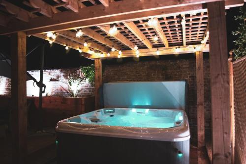 bañera de hidromasaje bajo una pérgola con luces en Cheesemans Farm Stables en Manston