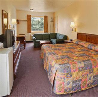 a hotel room with a bed and a couch and a tv at Belmont Inn and Suites in Hampton