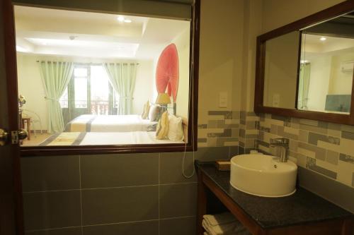 富國的住宿－貝拉富國度假酒店，一间带水槽的浴室和一张带镜子的床