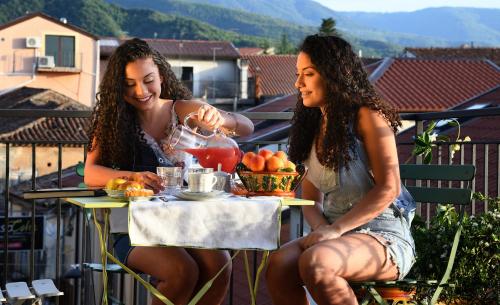 two women sitting at a table on a balcony at B&B Diana in Cittanova