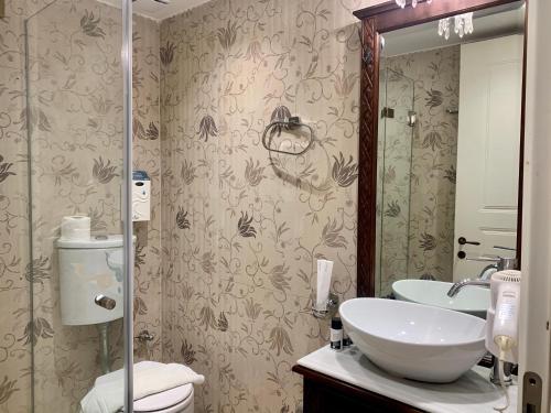 a bathroom with a sink and a toilet and a mirror at PortaDelMare deluxe suites in Hydra