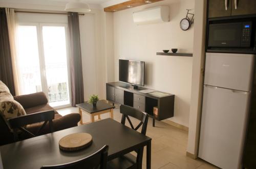 pequeña sala de estar con mesa y cocina en Apartamentos RuiSol - AUTO CHECKIN - by Centrall alquileres turísticos, en Nerja