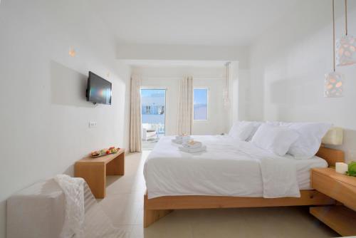a white bedroom with a large bed and a balcony at Petinos Hotel in Platis Yialos Mykonos