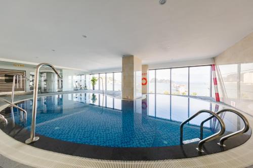 a large swimming pool in a building with a large window at Muong Thanh Grand Bai Chay in Ha Long