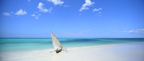 a sailboat on a beach with a sky background at Sultan Sands Island Resort in Kiwengwa