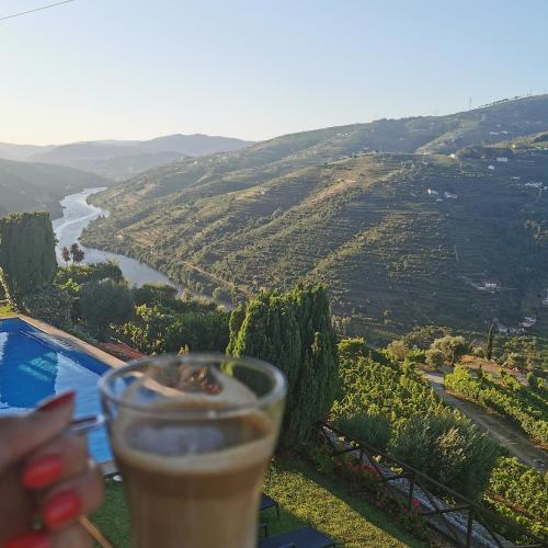 a hand holding a drink with a view of a river at Casa De Canilhas in Mesão Frio