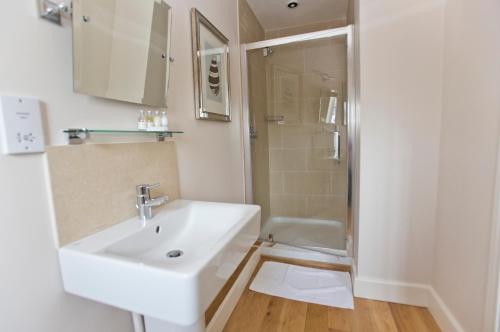 een witte badkamer met een wastafel en een douche bij Devonshire Arms in Langport