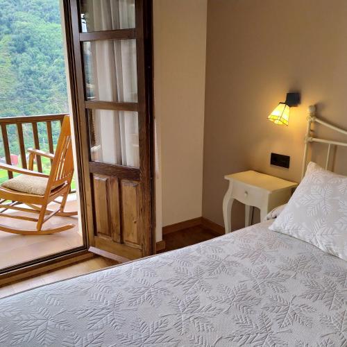 a bedroom with a bed and a chair and a window at Camin de Muniellos apartamentos rurales in Cangas del Narcea