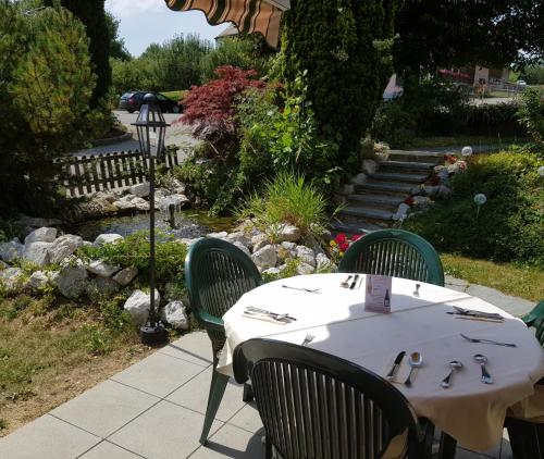 a table with green chairs sitting next to a garden at Hôtel Restaurant le Gruyérien in Morlon