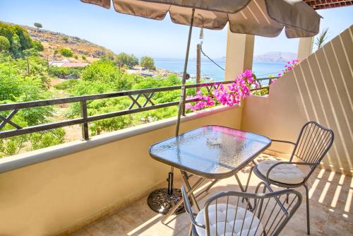 een tafel en stoelen op een balkon met uitzicht op de oceaan bij Haraki Sand Beach in Charaki