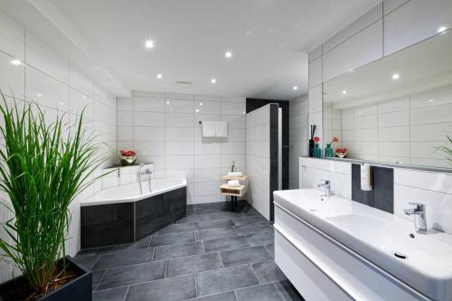 a bathroom with two sinks and a tub and a mirror at Stadthotel Borken in Borken