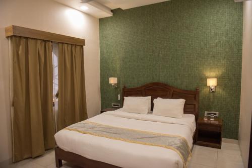 a bedroom with a bed and a green wall at Sun Hotel and Resort, Mount Abu in Ābu Road