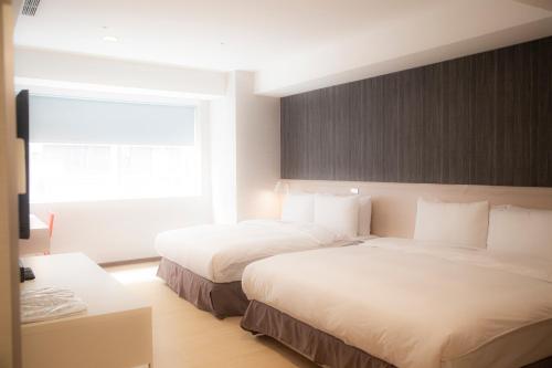 a hotel room with two beds and a window at HATAGO+ THE ALLEY in Taipei