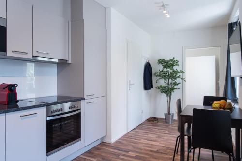 a kitchen with white cabinets and a table and a dining room at HITrental Wiedikon Apartments in Zürich