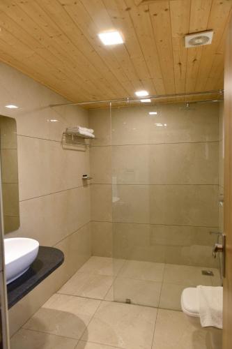 a bathroom with a glass shower with a toilet and a sink at Sun Hotel and Resort, Mount Abu in Ābu Road