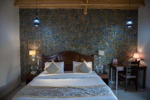 a bedroom with a bed and a desk with a chair at Sun Hotel and Resort, Mount Abu in Ābu Road