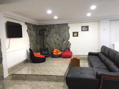 uma sala de estar com um sofá preto e cadeiras vermelhas em Guesthouse Gera em Mestia