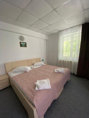 1 dormitorio con 1 cama grande y 2 toallas. en Pensiunea Ambasador, en Băile Herculane