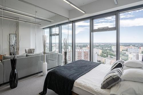 1 dormitorio con 1 cama grande y ventanas grandes en RentPlanet - Apartamenty Sky Tower, en Wroclaw