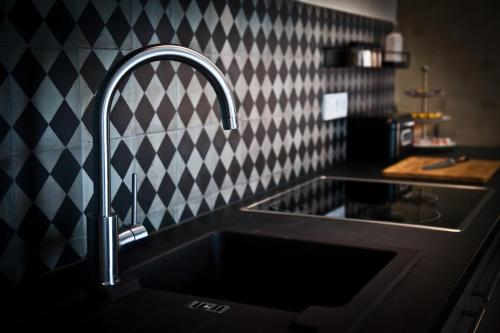 a sink in a kitchen with a checkered wall at Lohwald-Appartment in Oberwürschnitz