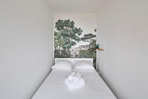a white bed with two white towels on it at L'Opalin by Cocoonr - en plein cœur de Dinard in Dinard
