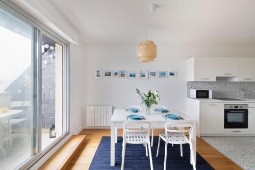 - une cuisine blanche avec une table et des chaises blanches dans l'établissement L'Opalin by Cocoonr - en plein cœur de Dinard, à Dinard