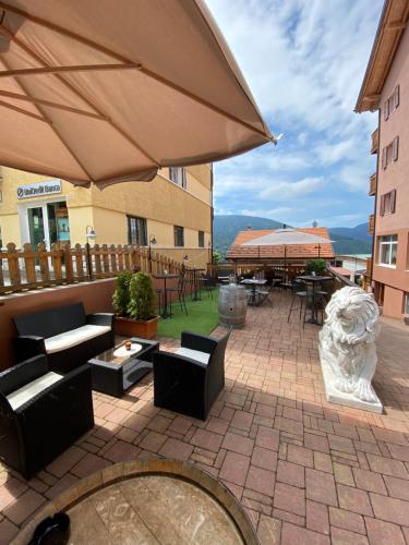 eine Terrasse mit Tischen, Stühlen und einem Sonnenschirm in der Unterkunft Folgaria Post Hotel in Folgaria