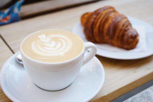 eine Tasse Kaffee und ein Croissant auf dem Tisch in der Unterkunft Jungle 13 - Room and Apartments in Neapel