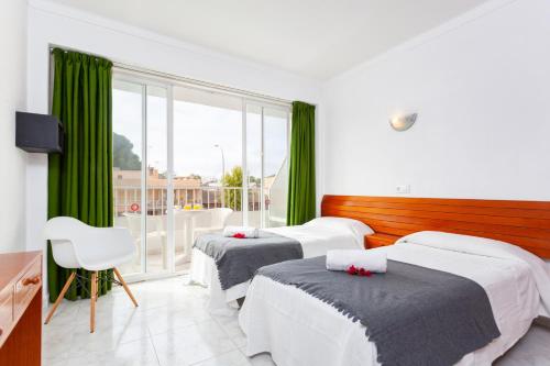 2 camas en una habitación con cortinas verdes en Africamar, en Can Picafort