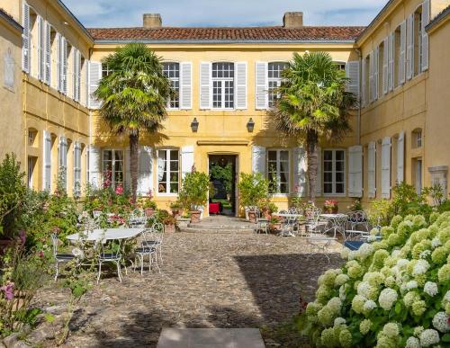 un patio con mesas y sillas frente a un edificio en La Baronnie Hôtel & Spa - Teritoria, en Saint-Martin-de-Ré