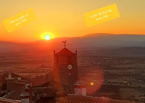 a clock tower with the sunset in the background at CASA DO CASTELLO MONSANTO in Monsanto