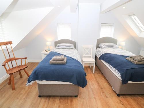 two beds in a attic bedroom with a chair at One Dolfor in Pwllheli