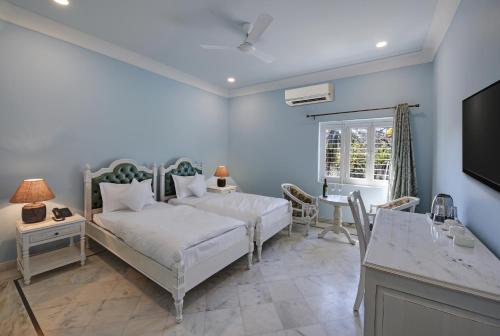 a bedroom with a bed and a table and a tv at The Mount Bungalow Mount Abu in Mount Ābu