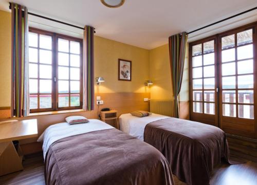 a hotel room with two beds and two windows at Hôtel La Clairière in Chambon-sur-Dolore