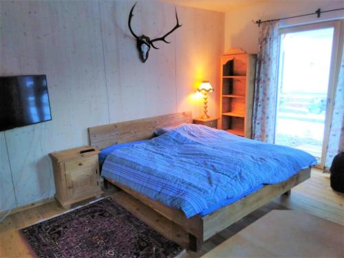 una camera da letto con un letto con un piumone blu e una finestra di Country Appartement Lungau a Sankt Margarethen im Lungau