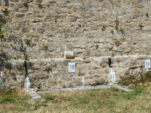 a stone wall with two numbered signs and a fountain at Zupan 1 - apartman in Krk