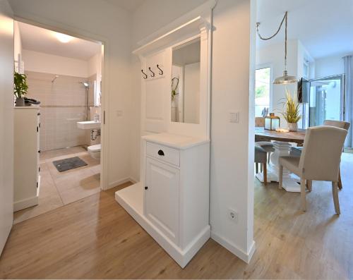 a white kitchen and dining room with a dining table at Ferienwohnung TreibGood in Glowe