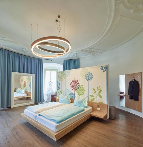 a bedroom with a large bed and a chandelier at Schloss Weinberg in Kefermarkt