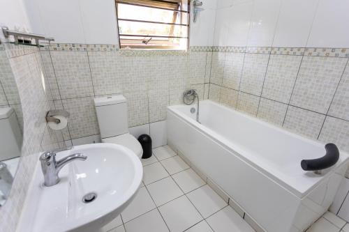 a bathroom with a sink and a tub and a toilet at Nzubo Experience in Livingstone
