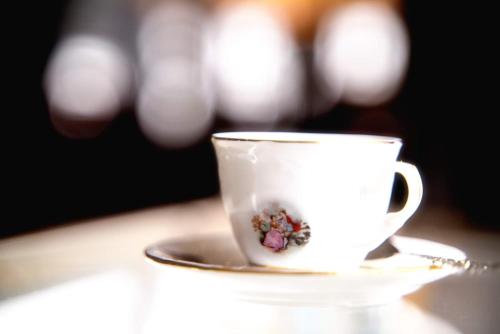 a white coffee cup on a saucer on a table at Gästehaus Brinks in Bad Sassendorf