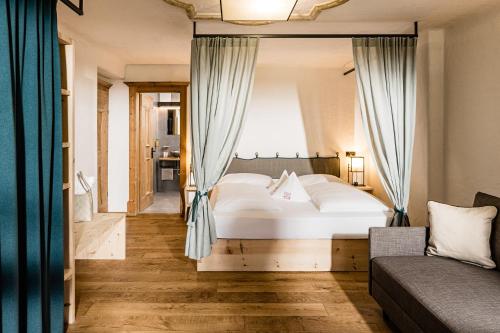 a bedroom with a large white bed and a couch at Mountain Resort Patzenfeld in Sesto